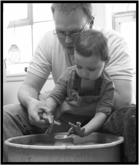 Tyler, the potter, helping his daugther create her first vase.